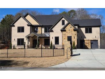 Two-story brick home with black trim, black metal fence, stone accents, a black roof and two-car garage at 1798 Braselton Hwy, Lawrenceville, GA 30043