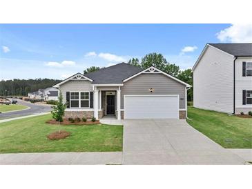 Charming one-story home showcasing a well-manicured lawn and a two-car garage, embodying suburban comfort at 8590 Secretariat Dr, Lithonia, GA 30058