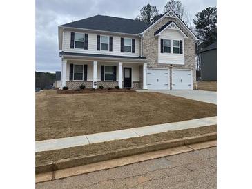 Two-story home features a brick and siding facade, dark shutters, a two-car garage and manicured lawn at 738 Great Oak Pl, Villa Rica, GA 30180