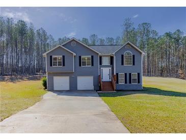 Charming two-story home with a two-car garage and a well-manicured lawn surrounded by mature trees at 1004 Hamilton Dr, Locust Grove, GA 30248