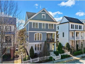 Charming three-story home with a welcoming front porch, beautiful landscaping, and a white picket fence at 203 Hubbard Rd, Woodstock, GA 30188