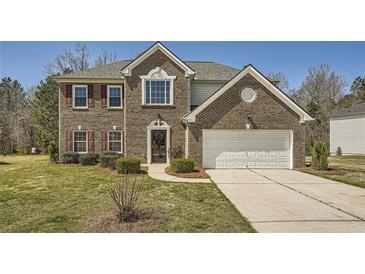 Charming two-story brick home with attached two-car garage, lush lawn and manicured shrubs at 4157 Medlock Woods Dr, Snellville, GA 30039