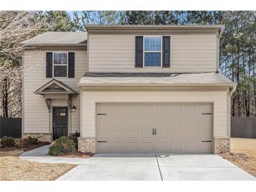 Two-story home featuring a 2-car garage, and black trimmed windows, complemented by neutral siding and a well-maintained lawn at , Fairburn, GA 30213