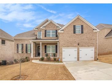 Inviting two-story brick home featuring a manicured lawn, two-car garage, and charming front porch at 2031 Broadmoor Way, Fairburn, GA 30213