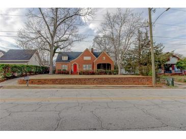 Charming brick home featuring a red door, well-maintained lawn, and classic architectural details at 2141 Conyers Se St, Covington, GA 30014