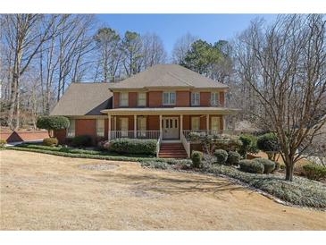 Charming brick home featuring a welcoming front porch, manicured lawn and mature landscaping at 3290 Spain Rd, Snellville, GA 30039