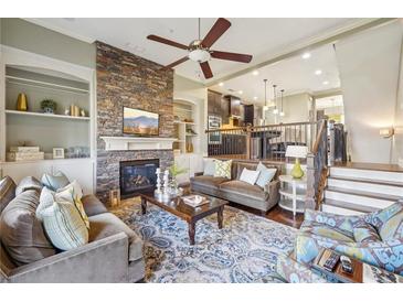 Bright living room featuring a stone fireplace, built-in shelving, and comfortable seating with a ceiling fan at 255 Southerland Ne Ter # 207, Atlanta, GA 30307