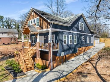 Two-story home featuring a welcoming elevated front porch with wooden stairs and blue painted wood with cedar shake accents at 1985 Lois Pl, Atlanta, GA 30318