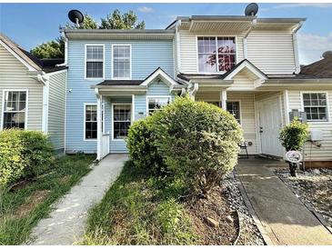 Charming townhome with light blue and beige siding, inviting front porch, and well-maintained landscaping at 5916 Dogwood Mnr, Lithonia, GA 30038