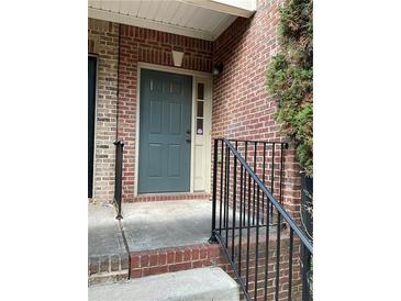 Charming front door of a brick home with gray paint, and a decorative railing on a sunny day at 5027 Bayrose Cir # 27A, Atlanta, GA 30344