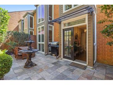 Stone patio with a grill, table with chairs, a fountain, and an entrance into the house at 17 Willow Ne Gln, Atlanta, GA 30342