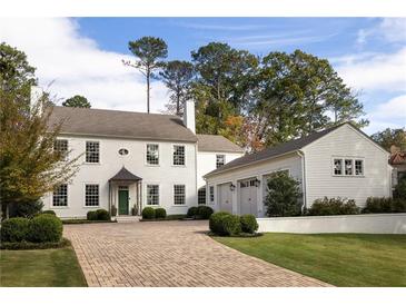 Elegant white home featuring a brick driveway, green lawn, and attached three-car garage at 2629 Ashford Ne Rd, Brookhaven, GA 30319