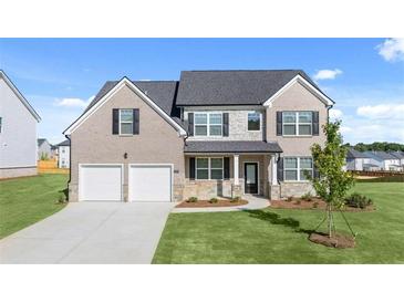 Charming two-story home featuring a two-car garage, brick accents, and a well-manicured lawn at 310 Aspen Valley Dr, Loganville, GA 30052