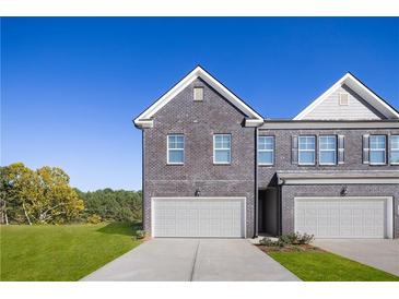 Modern townhome with a gray brick facade, two-car garage, and well-maintained lawn at 225 Epping St # 92, Stockbridge, GA 30281