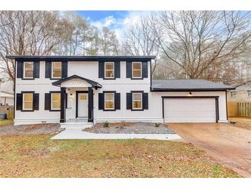 Charming two-story home featuring a fresh white paint, black shutters, and an attached garage at 2328 Carnes Rd, Jonesboro, GA 30236