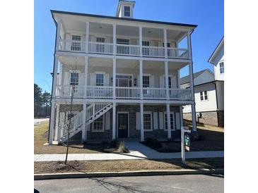 Charming three-story home featuring a welcoming porch, white railings, and classic architectural details at 1254 Six Sisters St, Dacula, GA 30019