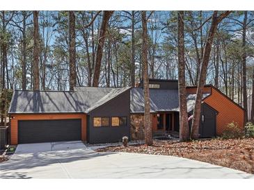 Charming exterior view of a two-story home with a well-maintained lawn, dark grey garage door, and mature trees at 320 Spyglass Blf, Alpharetta, GA 30022