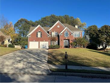 Charming two-story red brick home featuring a well-maintained front yard and a two-car garage at 3381 Walkers Ridge Rd, Dacula, GA 30019