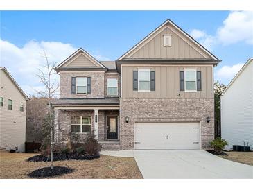 Two-story home with brick and siding, featuring a two-car garage and landscaped front yard at 106 Logan Pass Dr, Loganville, GA 30052