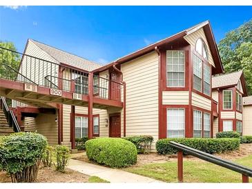 Inviting two-story condo with beige siding, red trim, a balcony, and lush landscaping at 904 Wentworth Ct, Alpharetta, GA 30022