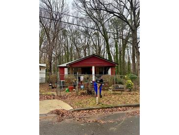 Red single-story home with a fenced front yard on a cloudy day at 3230 Altacrest Dr, Scottdale, GA 30079