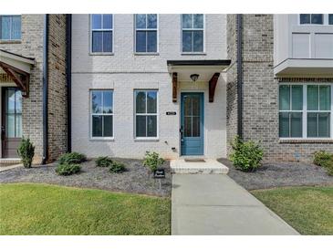 Charming townhome with a blue front door and painted white brick facade with a manicured lawn at 4320 Sims Park Overlook, Suwanee, GA 30024