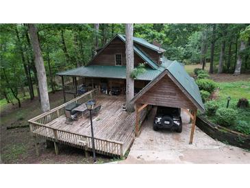 Charming home featuring a wooden deck, carport, and wooded surroundings, creating a serene and private outdoor space at 6245 Bannister Rd, Cumming, GA 30028
