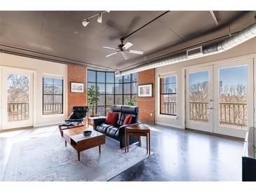 Bright living room featuring a large window, exposed brick wall, and open layout with an industrial design at 395 Central Park Ne Pl # 420, Atlanta, GA 30312