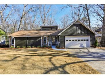 Charming single-story home featuring a two-car garage, stone accents and manicured front lawn at 645 Trailmore Pl, Roswell, GA 30076