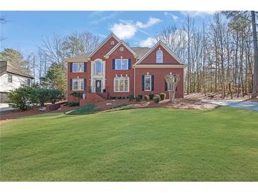 Charming two-story brick home featuring a well-manicured lawn, complemented by mature trees and beautiful landscaping at 455 Emerald Lake Path, Sugar Hill, GA 30518