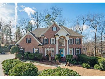 Charming brick home featuring a manicured lawn, lush landscaping, and a welcoming light blue front door at 6195 Mountainwell Dr, Roswell, GA 30075