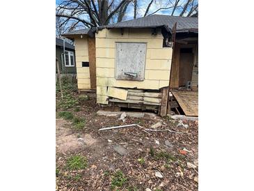 A deteriorated yellow home with boarded windows and visible damage to the siding and foundation at 1771 Hosea L Williams Se Dr, Atlanta, GA 30317