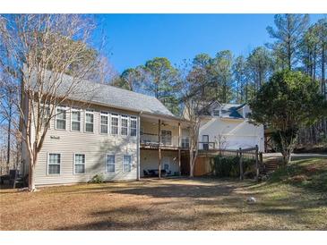 View of the home exterior with a sprawling backyard and wooded area at 8245 Mill Run Trl, Whitesburg, GA 30185