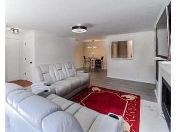 Bright living room featuring white leather sofas, gray floors, and a unique red rug at 709 Berkeley Woods Dr # 709, Duluth, GA 30096