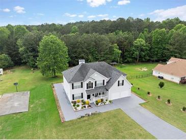 Inviting two-story home with a well-manicured lawn and a basketball court is nestled in a serene wooded setting at 709 Mohansic Ave, Loganville, GA 30052