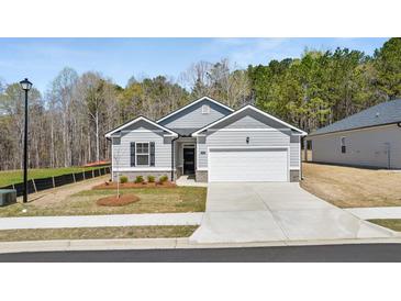 Charming single-story home featuring a gray exterior, attached garage, and landscaped front yard at 8592 Secretariat Dr, Lithonia, GA 30058