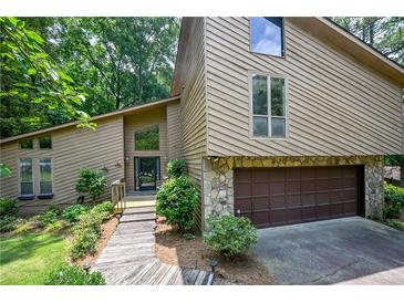 Charming home with a striking exterior, a stone-accented garage and a landscaped pathway at 2235 Six Branches Dr, Roswell, GA 30076