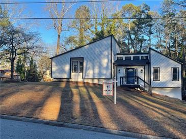 Charming modern home with fresh white siding and black accents, sitting atop a grassy, sloped front yard at 783 Lost Creek Cir, Stone Mountain, GA 30088