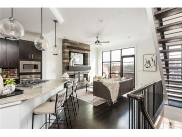 Open-concept living room with dark wood floors, modern fireplace, and spacious kitchen area at 1199 Huff Nw Rd # 109, Atlanta, GA 30318