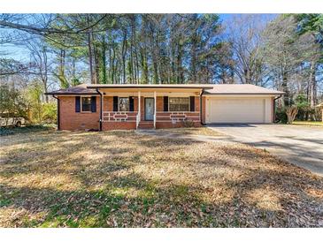 Charming brick home featuring an attached garage and cozy front porch at 1465 Rockbridge Rd, Stone Mountain, GA 30087