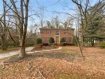 Charming two-story brick home featuring a manicured front lawn with mature trees at 1302 Milstead Ne Trce, Marietta, GA 30066