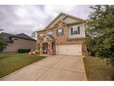 Charming two-story brick home with a two-car garage, green lawn, and tasteful fall decorations at 430 St Annes Pl, Covington, GA 30016