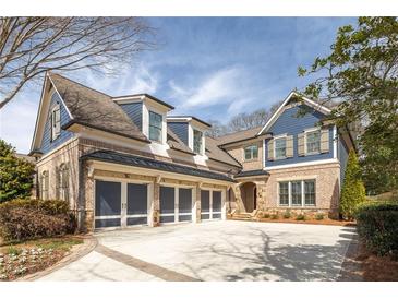 Beautiful brick home with blue accents, a curved driveway, a well-manicured lawn, and an attached three-car garage at 326 S Columbia Dr, Decatur, GA 30030