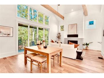 Bright living room with wooden floors, fireplace, large windows, and sliding door to an outdoor balcony at 1250 Lupo Loop, Palmetto, GA 30268