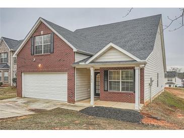 Two story home with a brick front, two car garage, and small manicured lawn at 4394 Estate St, Atlanta, GA 30349