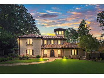 Beautiful stucco home with red tile roof, manicured lawn, mature trees, and walkway leading to the front door at 130 Woodlawn Ne Dr, Marietta, GA 30067