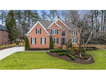 Charming two-story brick home with manicured lawn, mature trees, and beautiful landscaping at 832 Forest Path Ln, Alpharetta, GA 30022