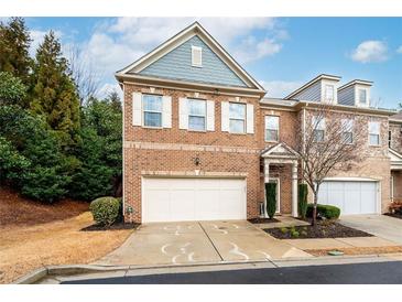 Charming brick townhome with a two-car garage and manicured landscaping on a beautiful day at 3557 Ashcroft Se Dr, Smyrna, GA 30080
