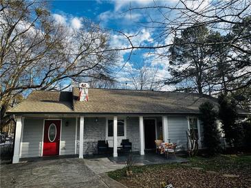 Charming single-story home with gray siding, red door, inviting front porch, and mature trees in a serene neighborhood at 3356 Hollow Ct, Lawrenceville, GA 30044