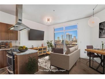 Bright living room with a modern sofa, open to a kitchen with stainless steel appliances and city views at 2626 Peachtree Nw Rd # 1102, Atlanta, GA 30305